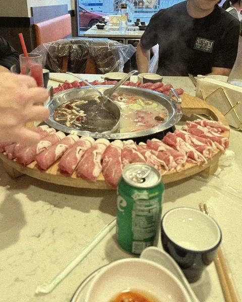A bubbling hot pot surrounded by plates of sliced meat