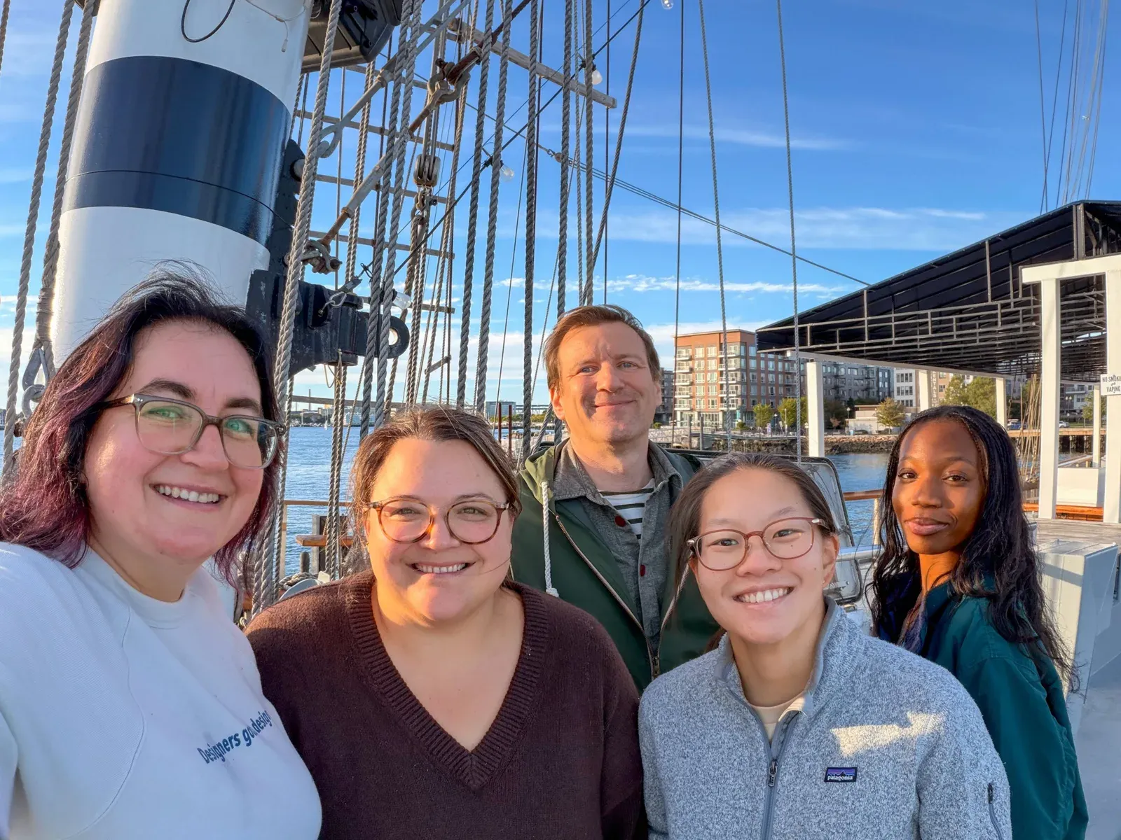 Jordan and four teammates taking a selfie in front of the tall ship’s mast and rigging